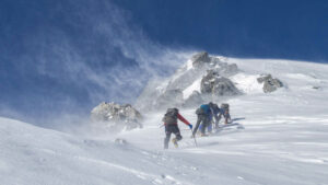 Trotz des schönen Wetters geht ein eisiger Wind. Die fünf Bergsteiger kämpfen sich auf dem verschneiten Berg zum schon nahen Gipfel.